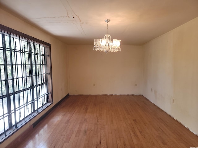 spare room with an inviting chandelier, dark wood-type flooring, and a wealth of natural light