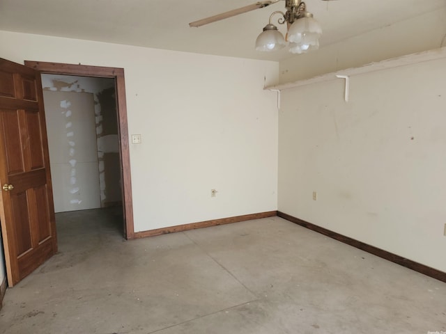 spare room featuring concrete floors and a chandelier