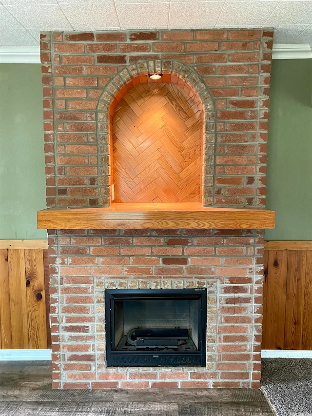 details with crown molding, a textured ceiling, a fireplace, and wooden walls