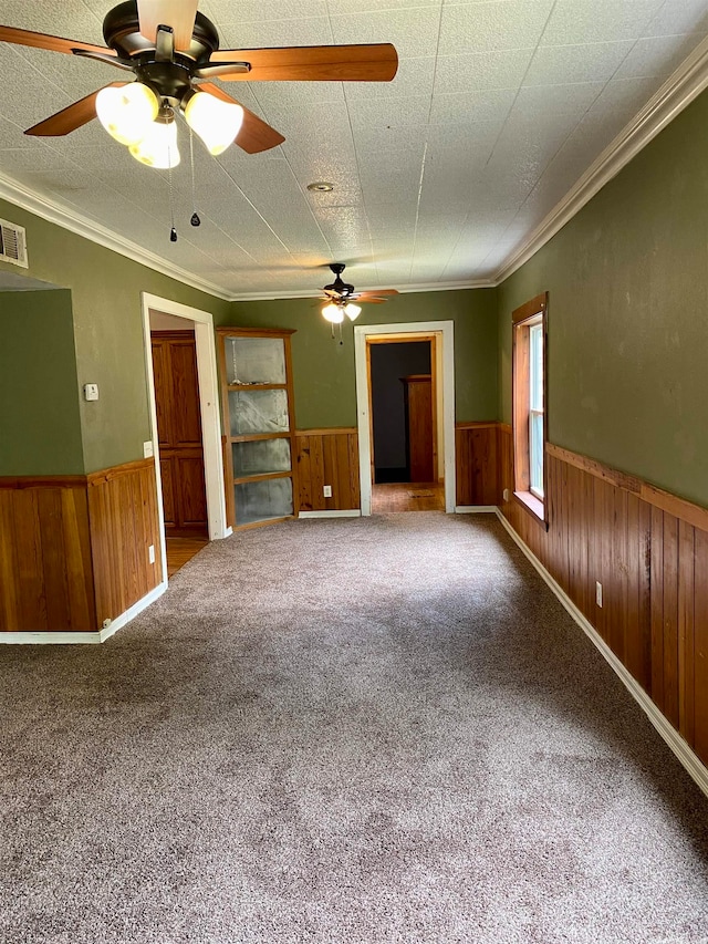 unfurnished living room featuring crown molding, carpet, and wood walls