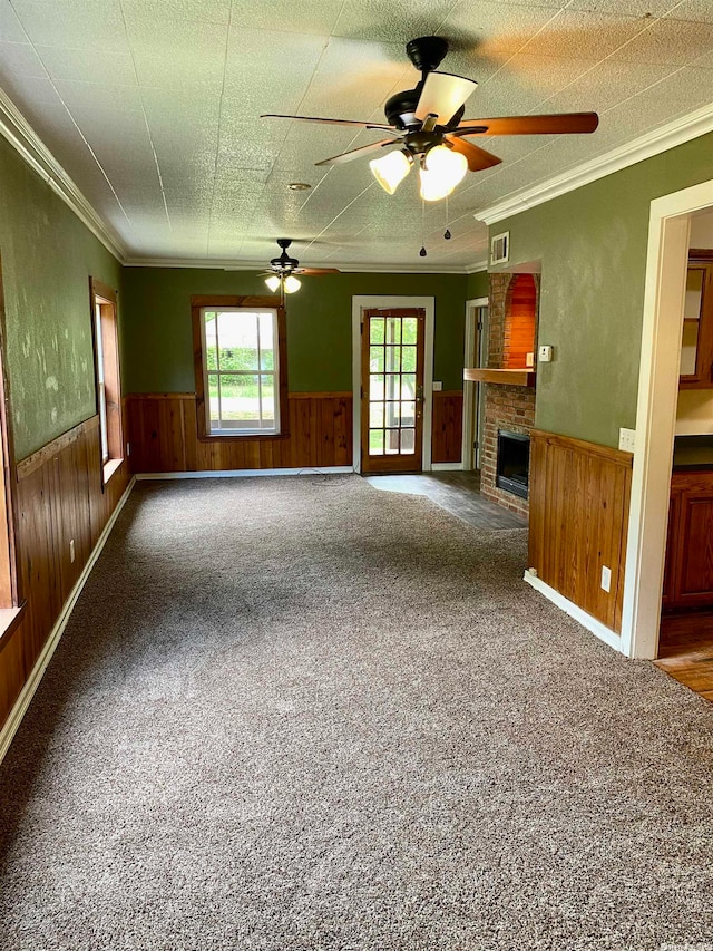 unfurnished living room with carpet floors, a wealth of natural light, a fireplace, and wood walls