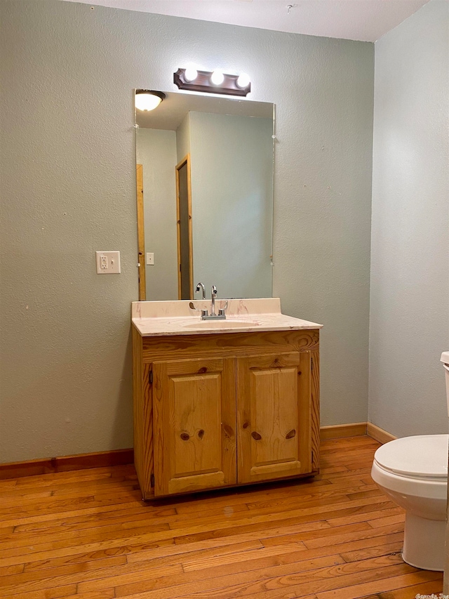 bathroom with wood-type flooring, toilet, and vanity