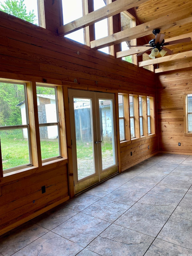 entryway with a towering ceiling, wooden walls, and french doors