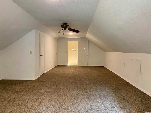 bonus room featuring vaulted ceiling, a textured ceiling, and dark colored carpet