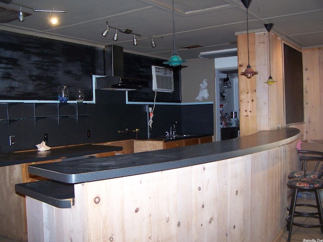 bar featuring a wall unit AC, wall chimney exhaust hood, sink, hanging light fixtures, and track lighting