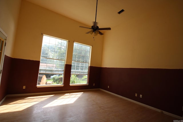 empty room with a healthy amount of sunlight, ceiling fan, and high vaulted ceiling