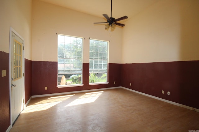 spare room with high vaulted ceiling, plenty of natural light, hardwood / wood-style floors, and ceiling fan