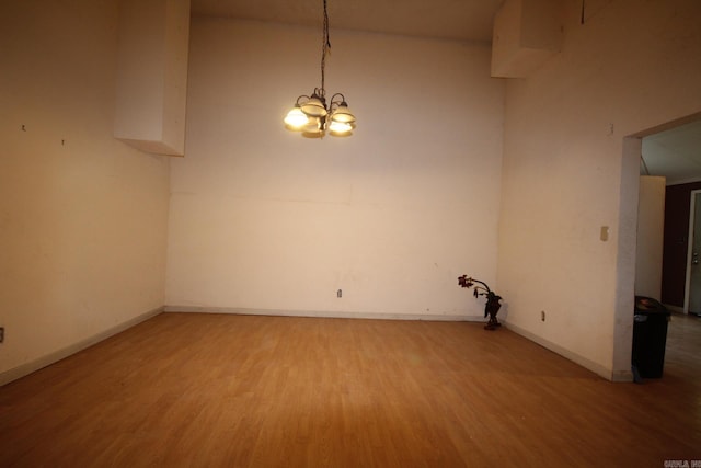 unfurnished room with hardwood / wood-style floors and a notable chandelier