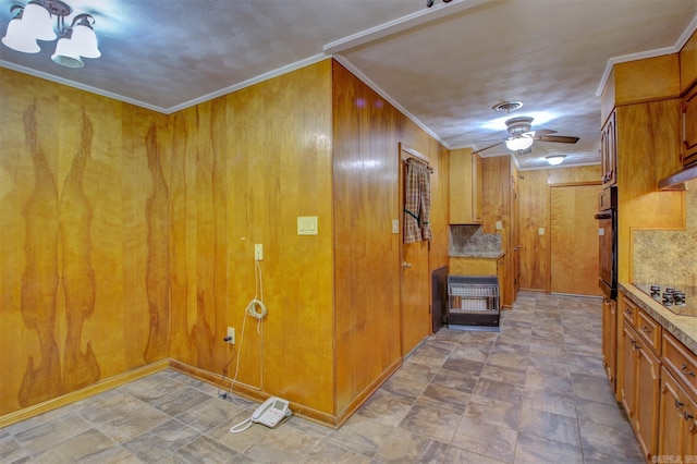 kitchen featuring ceiling fan, wooden walls, ornamental molding, and light tile floors