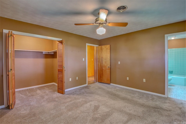 unfurnished bedroom with light colored carpet, ensuite bathroom, and ceiling fan