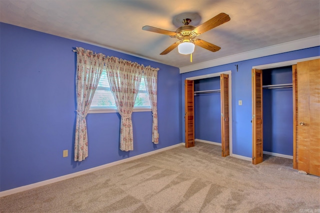 unfurnished bedroom with light carpet, two closets, and ceiling fan