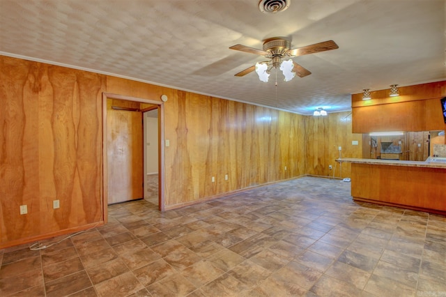 unfurnished living room featuring ceiling fan, wood walls, and light tile floors