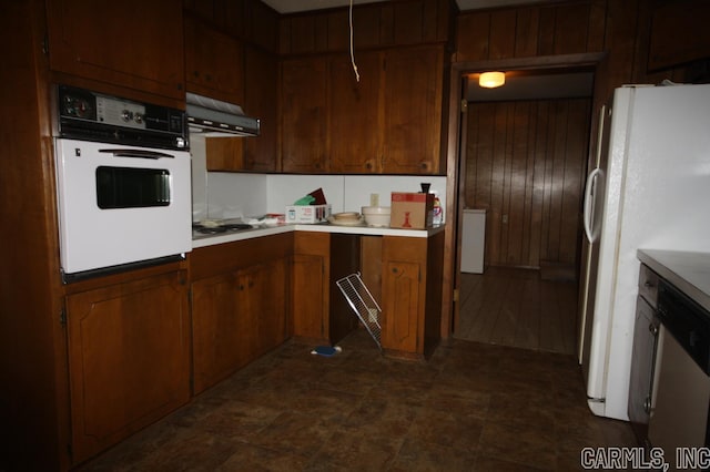 kitchen with dark tile flooring, white appliances, and wooden walls