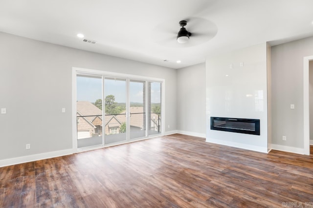 unfurnished living room with dark hardwood / wood-style flooring and ceiling fan