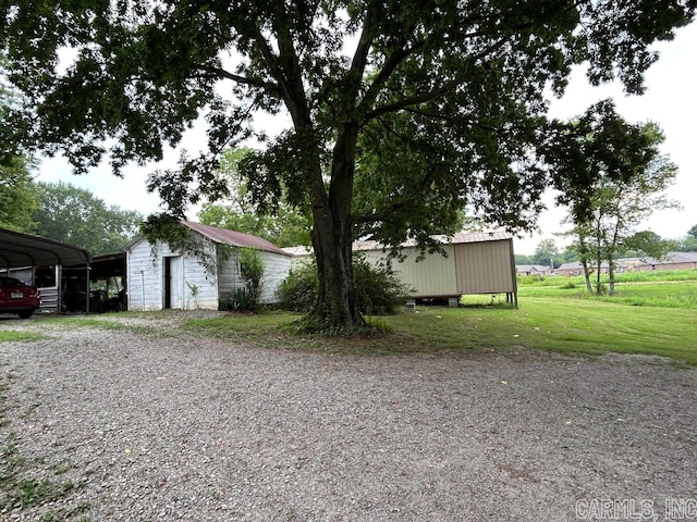 view of side of home featuring a carport, an outbuilding, and a lawn