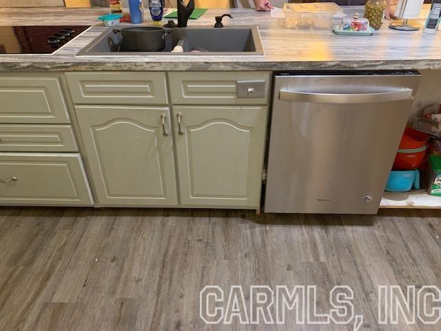 kitchen featuring sink, black electric stovetop, dishwasher, and hardwood / wood-style floors