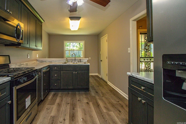 kitchen featuring ceiling fan, appliances with stainless steel finishes, sink, and wood-type flooring