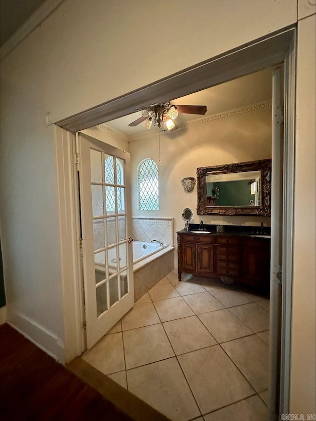 bathroom with dual vanity, ceiling fan, ornamental molding, tile floors, and tiled tub