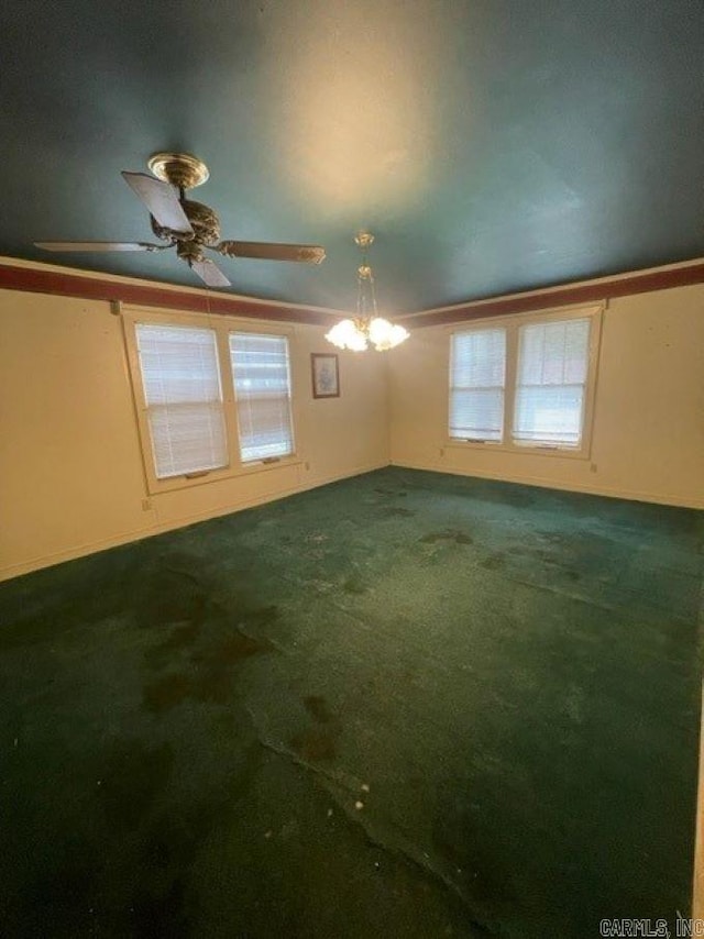 spare room featuring ceiling fan with notable chandelier and dark carpet