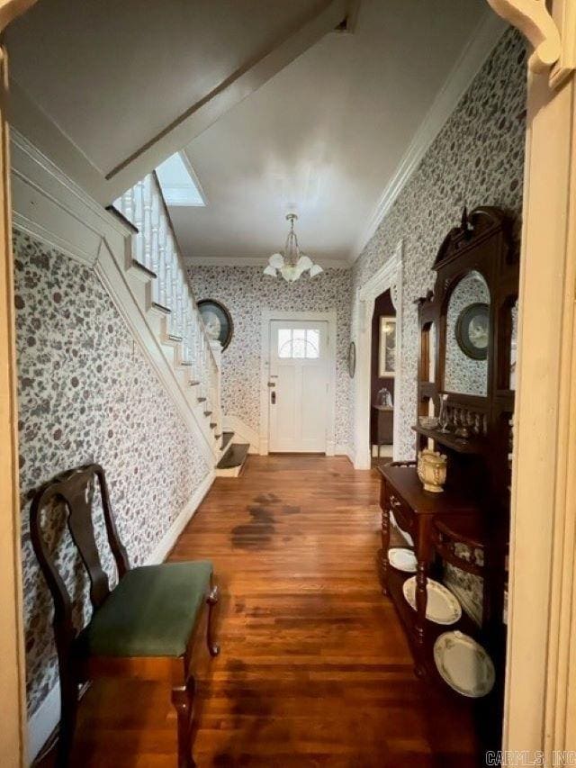 corridor featuring dark hardwood / wood-style flooring, a notable chandelier, and ornamental molding