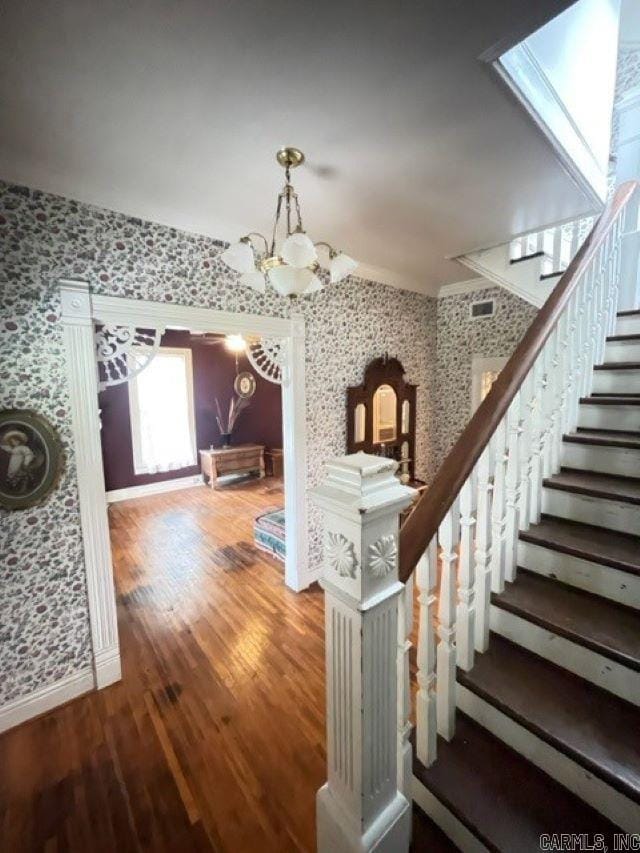 staircase featuring a skylight, dark wood-type flooring, and a notable chandelier