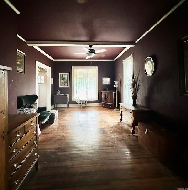 living area with ceiling fan, crown molding, dark wood-type flooring, and beam ceiling