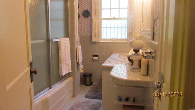 bathroom featuring tile walls, backsplash, and shower / bath combination with glass door