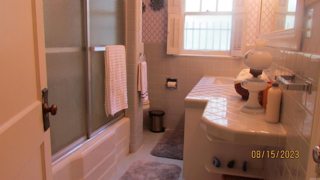 bathroom featuring tile walls, tasteful backsplash, and bath / shower combo with glass door