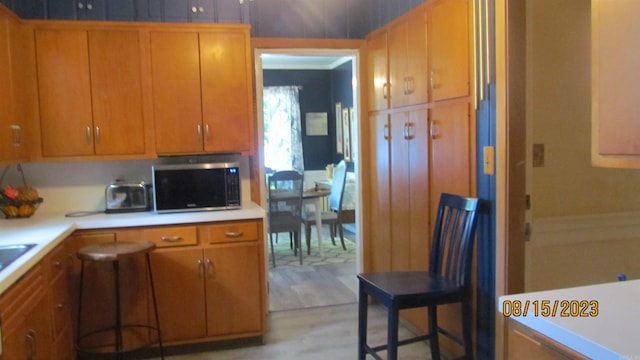 kitchen with a kitchen breakfast bar and light hardwood / wood-style flooring