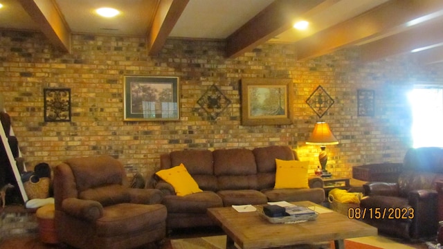 living room featuring beam ceiling and brick wall