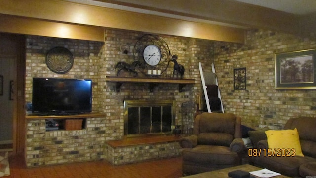 living room featuring beam ceiling, brick wall, and a brick fireplace