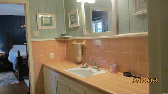 bathroom featuring backsplash, oversized vanity, and tile walls