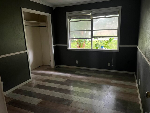 unfurnished bedroom featuring crown molding, a closet, and dark wood-type flooring