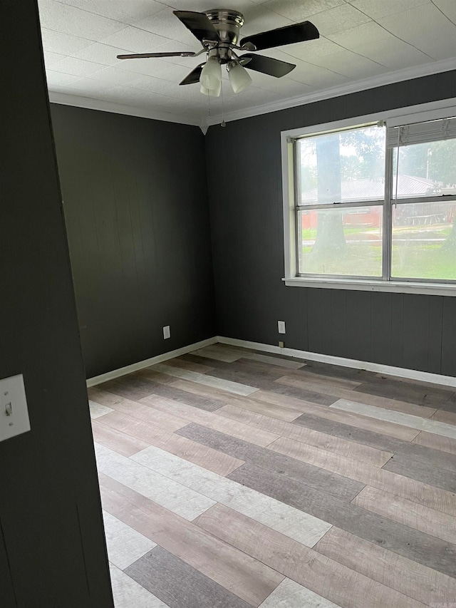 spare room featuring ceiling fan, crown molding, and light wood-type flooring