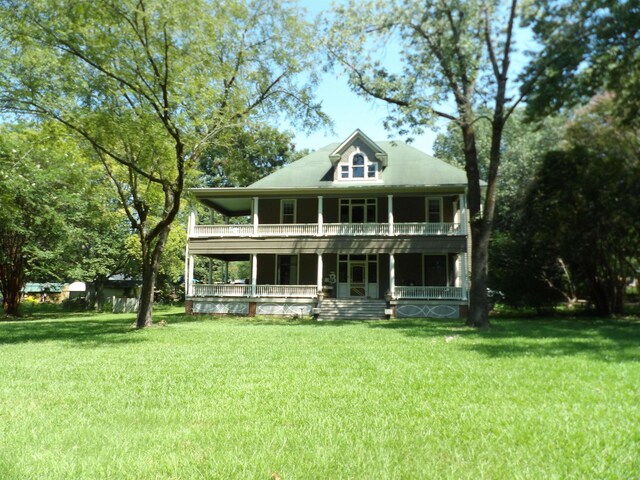 back of property featuring covered porch and a yard