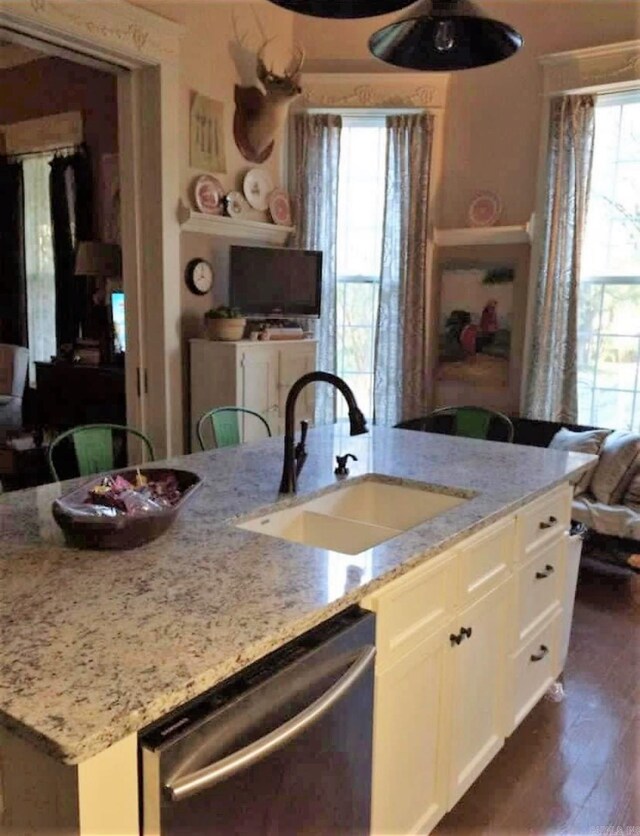 kitchen featuring stainless steel dishwasher, sink, light stone counters, and white cabinetry