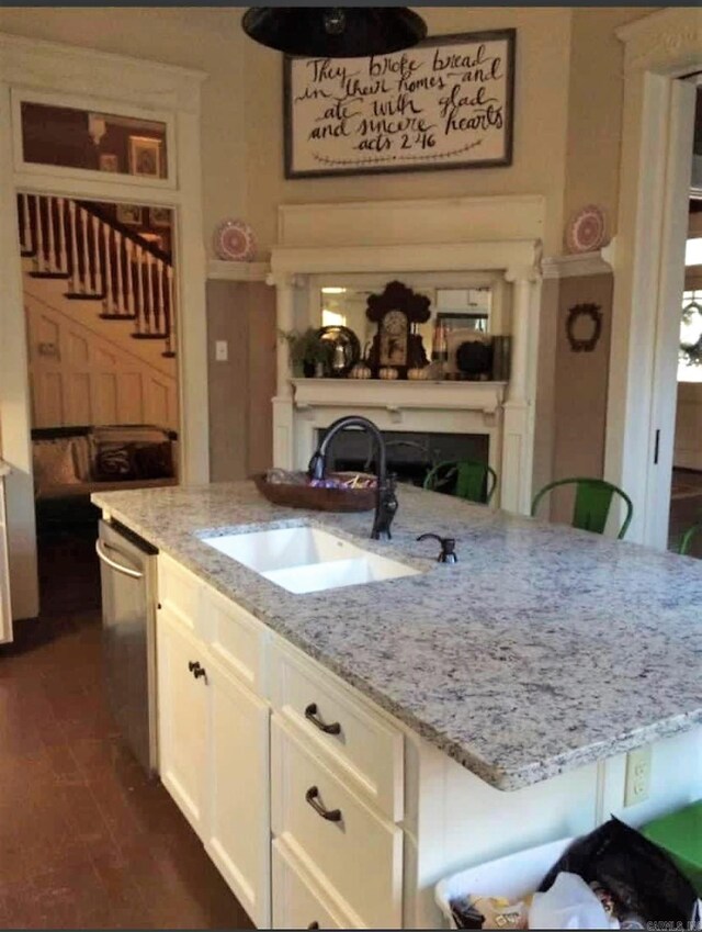 kitchen with light stone countertops, sink, stainless steel dishwasher, and white cabinetry