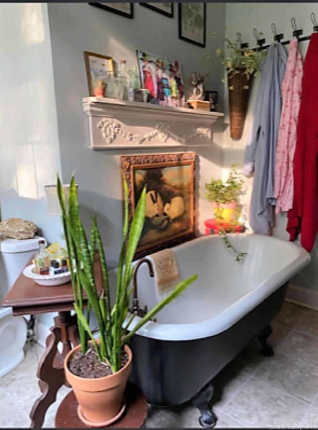 bathroom featuring a bath to relax in, tile flooring, and toilet