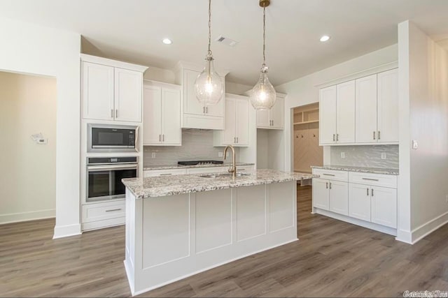 kitchen with appliances with stainless steel finishes, tasteful backsplash, white cabinetry, and dark wood-type flooring