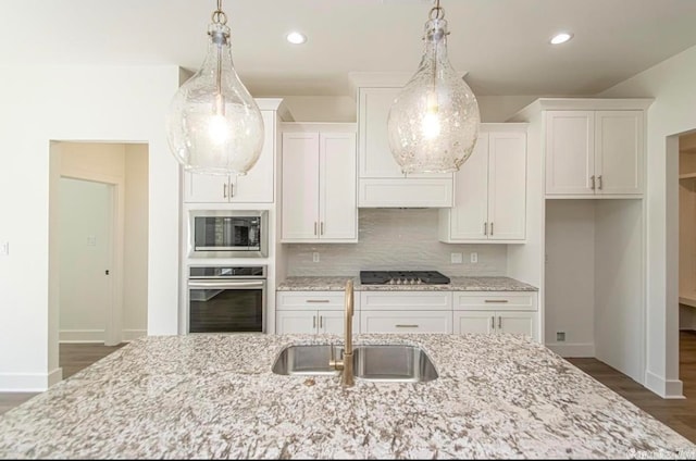 kitchen featuring decorative light fixtures, white cabinetry, appliances with stainless steel finishes, sink, and tasteful backsplash