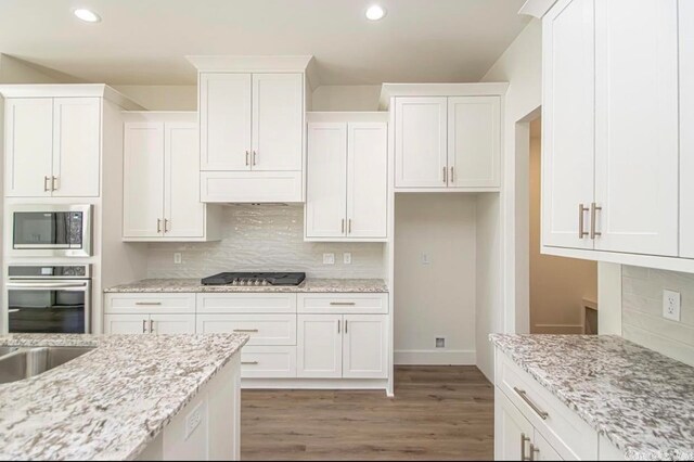 kitchen featuring white cabinetry, tasteful backsplash, stainless steel appliances, and wood-type flooring