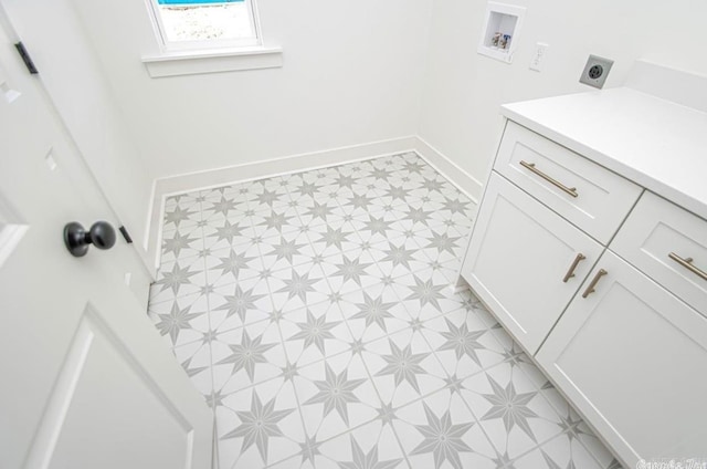 interior space featuring hookup for an electric dryer, cabinets, light tile floors, and hookup for a washing machine