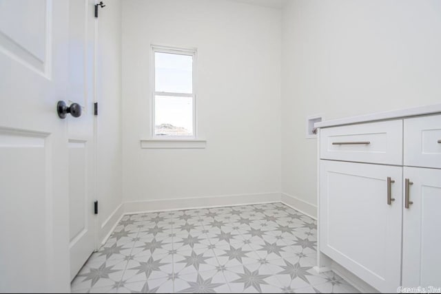 clothes washing area featuring washer hookup, cabinets, and light tile floors