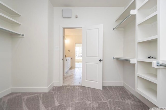 walk in closet with light carpet