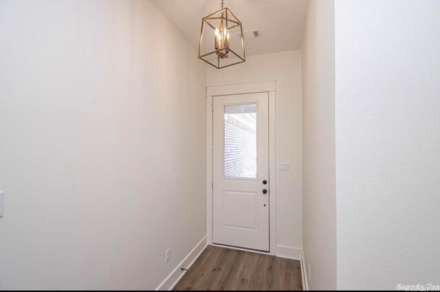 doorway to outside with dark hardwood / wood-style floors and a chandelier