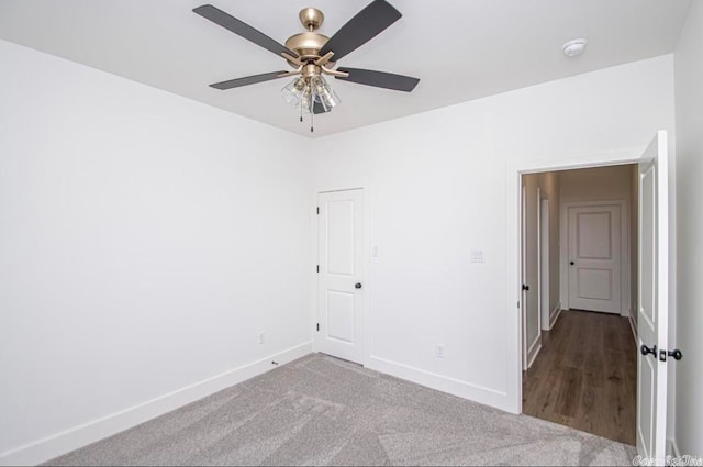 empty room with ceiling fan and dark colored carpet