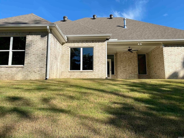 rear view of house with ceiling fan and a lawn