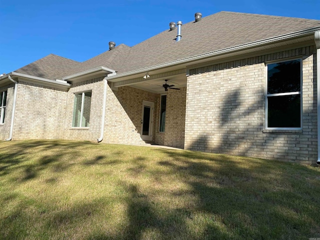 rear view of property featuring ceiling fan and a yard