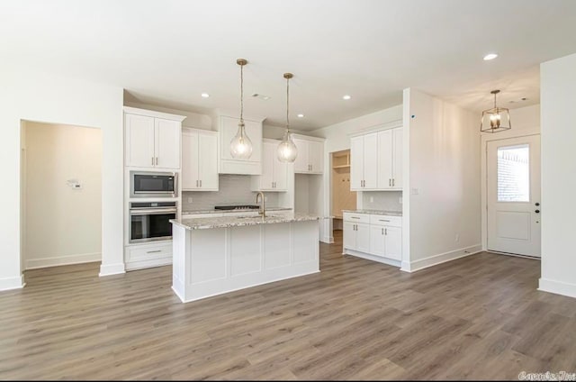 kitchen featuring white cabinets, a center island with sink, light hardwood / wood-style floors, and stainless steel appliances