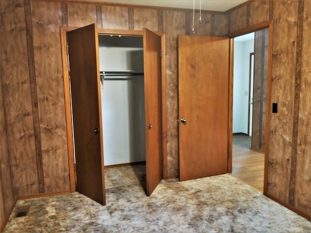 unfurnished bedroom featuring a closet, light hardwood / wood-style floors, and wooden walls